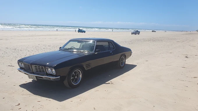 Restored classic Pontiac Firebird parked on the beach